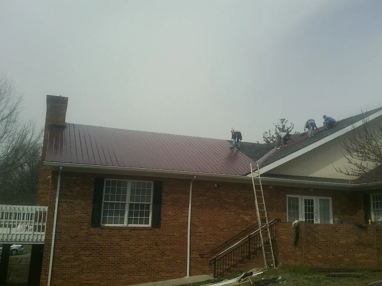 Crew setting red metal roofing panels on a brick home in Boca Raton