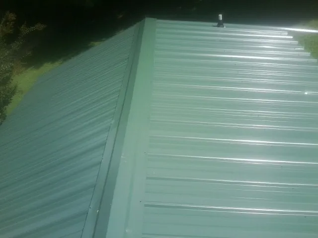 New green metal panels meeting at the ridge of a roof — Flat Roof Repair work by our crew in Boca Raton