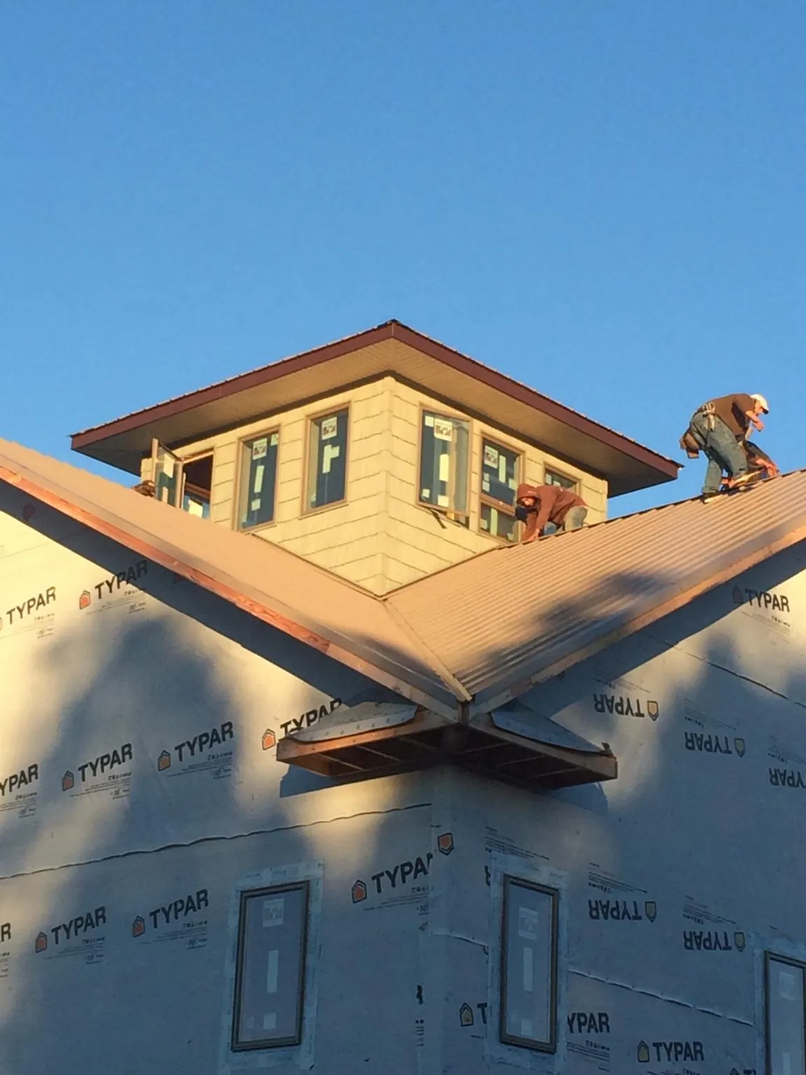 Roofers working around a rooftop cupola on a new metal roof at sunset — Roof Waterproofing in Boca Raton by Roofing Brothers
